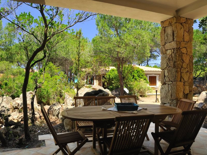 Überdachte Terrasse mit Esstisch in Teak und Blick in den Garten Überdachte Terrasse mit Esstisch in Teak und Blick in den Garten
