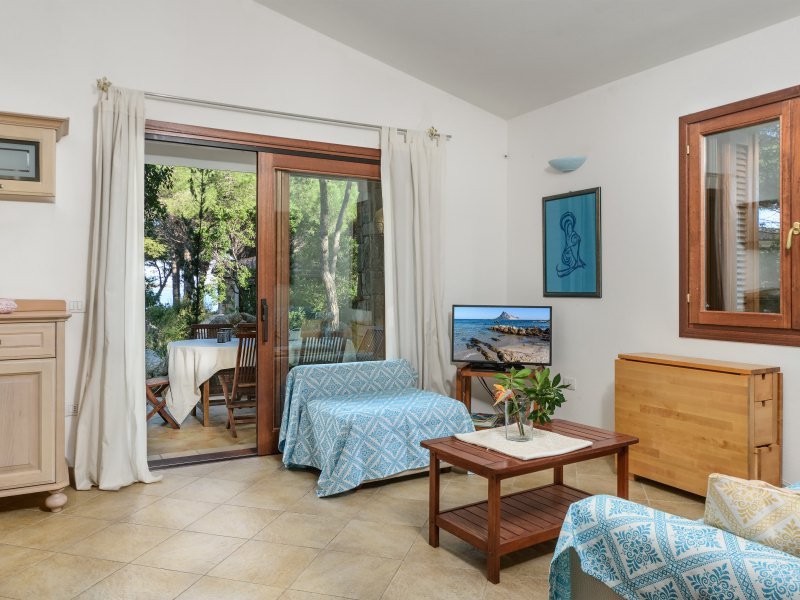 Wohnzimmer mit Sofas, TV und Tür zur Terrasse mit Esstisch Wohnzimmer mit Sofas, TV und Tür zur Terrasse mit Esstisch