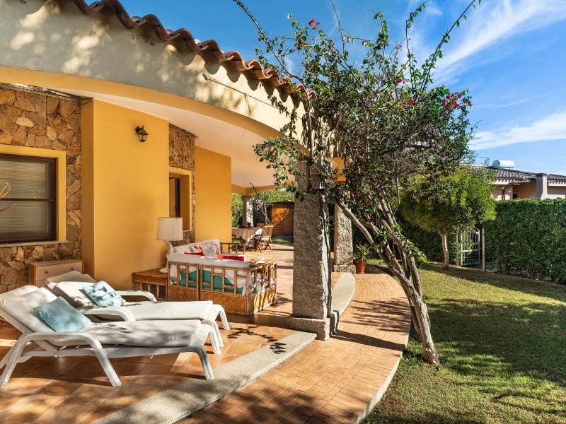 Terrasse rund um einen Teil des Hauses mit gemütlichen Sonnenliegen, Außensofa, Esstisch und Garten Terrasse rund um einen Teil des Hauses mit gemütlichen Sonnenliegen, Außensofa, Esstisch und Garten