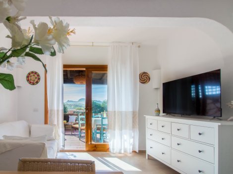 Hell eingerichtetes Wohnzimmer mit Blick auf die atemberaubende Landschaft Sardinien